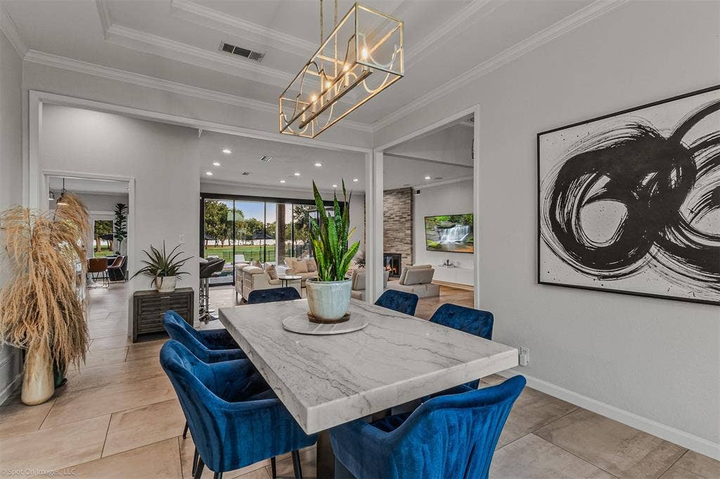 28 Victoria Drive, Rowlett, TX 75088 Tray ceiling with crown molding, linear chandelier, light-toned tile flooring, and a marble-finish tabletop