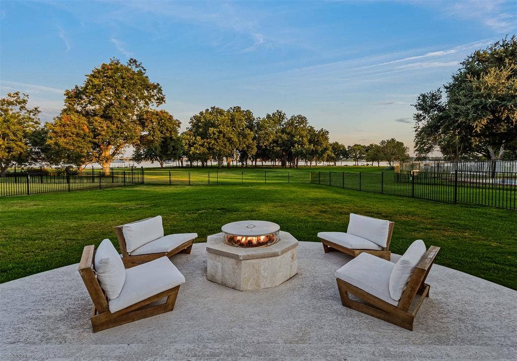 28 Victoria Drive, Rowlett, TX 75088 Expansive backyard featuring a stone fire pit, concrete patio, and a black metal fence