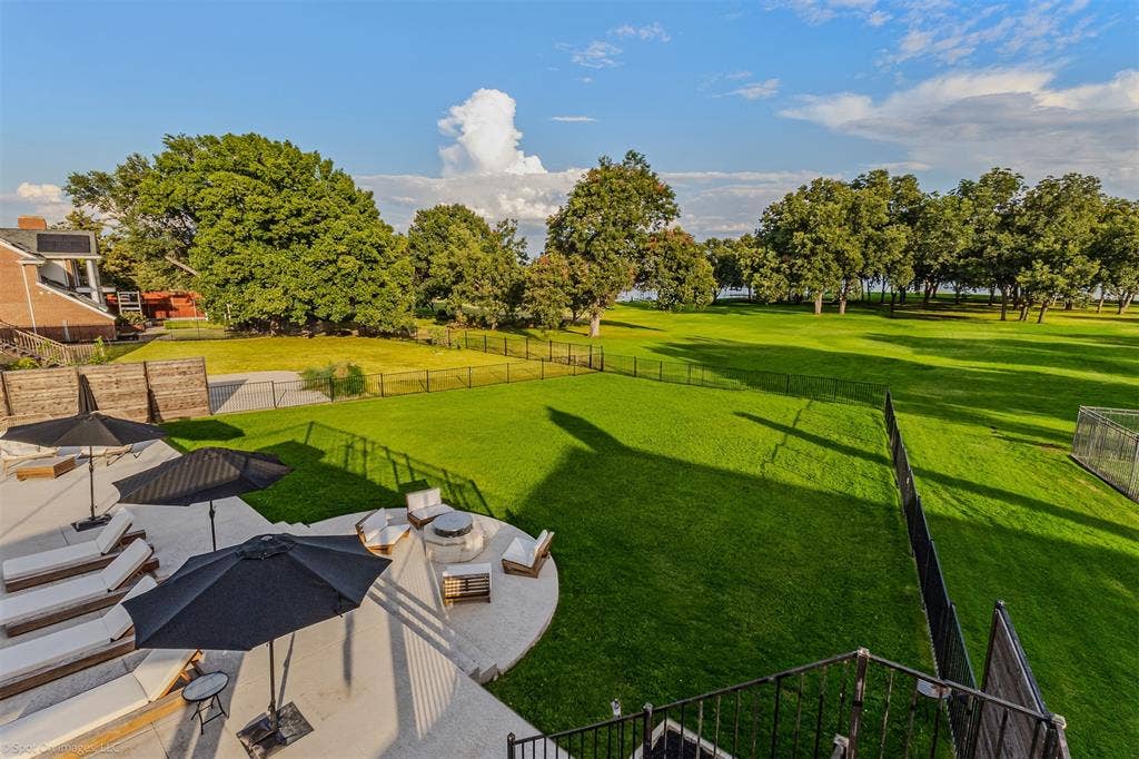 28 Victoria Drive, Rowlett, TX 75088 Expansive concrete patio with a built-in fire pit, surrounded by lush green lawn and mature trees