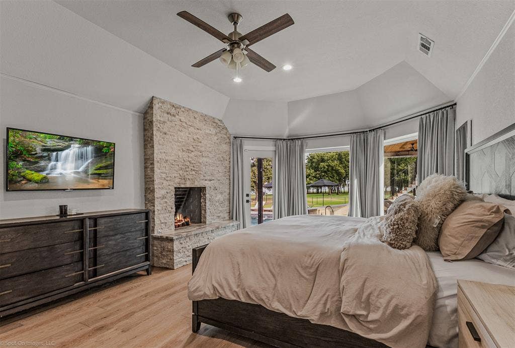 28 Victoria Drive, Rowlett, TX 75088 Vaulted ceiling with a ceiling fan, stone-clad fireplace, wood-finish flooring, and multiple windows