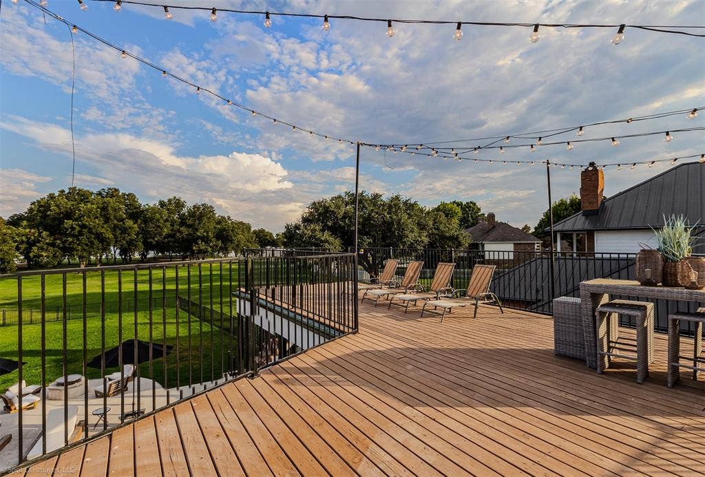 28 Victoria Drive, Rowlett, TX 75088 Expansive outdoor deck featuring wood-finish flooring, black metal railings, and string lighting