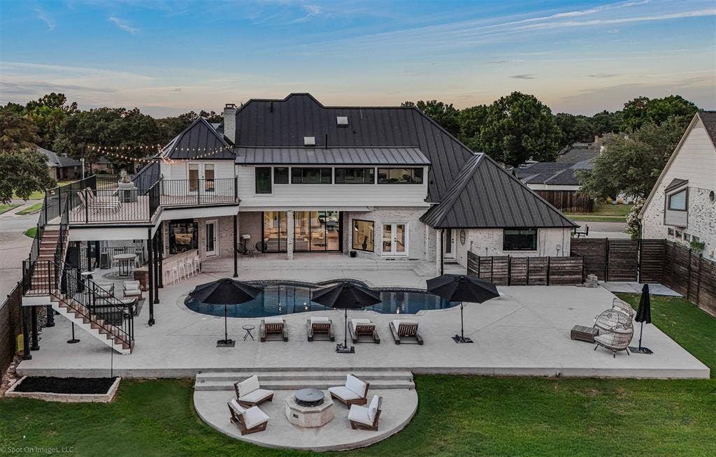 28 Victoria Drive, Rowlett, TX 75088 Resort-style backyard featuring a dark-bottom swimming pool, extensive concrete patio, and a dedicated fire pit area