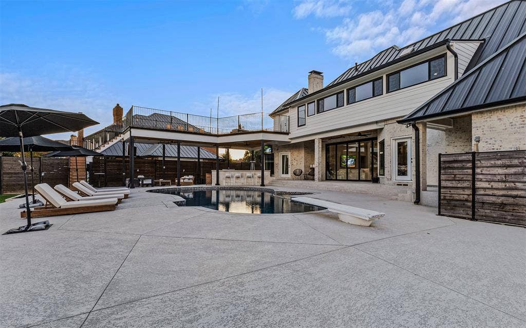 28 Victoria Drive, Rowlett, TX 75088 Expansive concrete patio with a built-in swimming pool, integrated diving board, and an outdoor kitchen area under a covered structure
