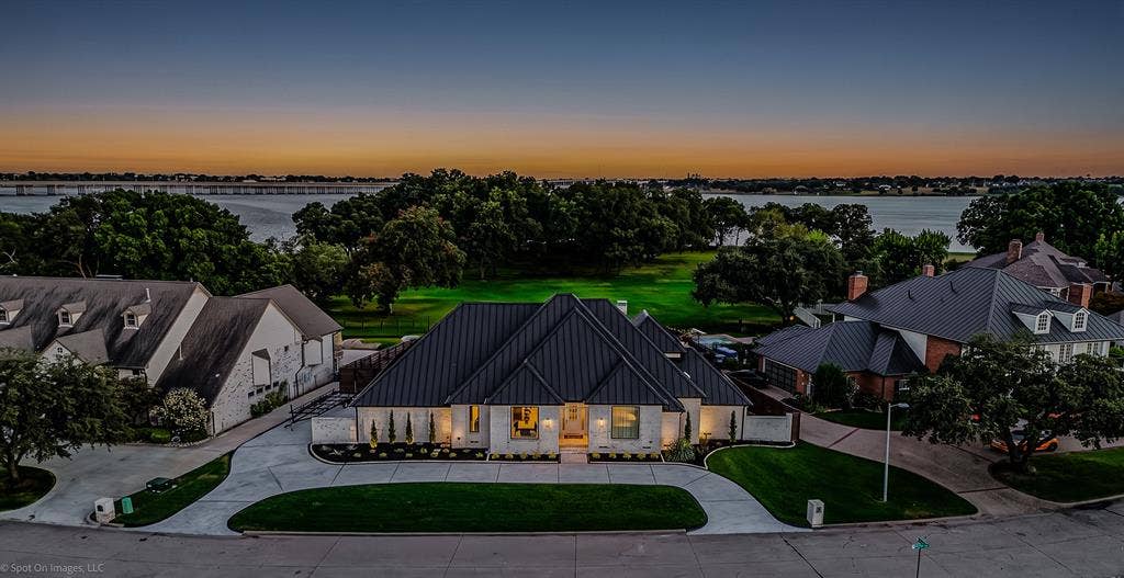 28 Victoria Drive, Rowlett, TX 75088 Modern architecture featuring a dark metal roof, light-colored stone facade, and a curved driveway
