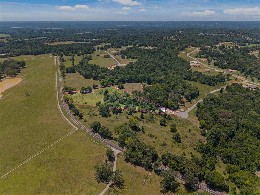 16713 Creek Bottom Court, Winona, TX 75792 Expansive property featuring a mix of open fields and mature trees, with a visible railroad track running alongside