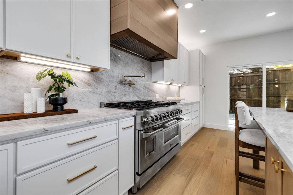 4402 Briargrove Lane, Dallas, TX 75287 4402 Briargrove-White shaker cabinetry with designer hardware, a 48-inch stainless steel range, and a custom statement range hood.