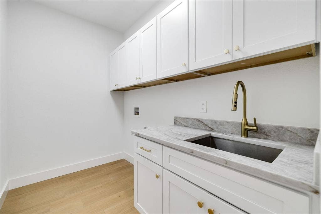 4402 Briargrove Lane, Dallas, TX 75287 4402 Briargrove-White shaker cabinetry paired with wide-plank white oak flooring, an undermount sink, brass-tone fixtures, and Calacatta Taj quartz countertops.