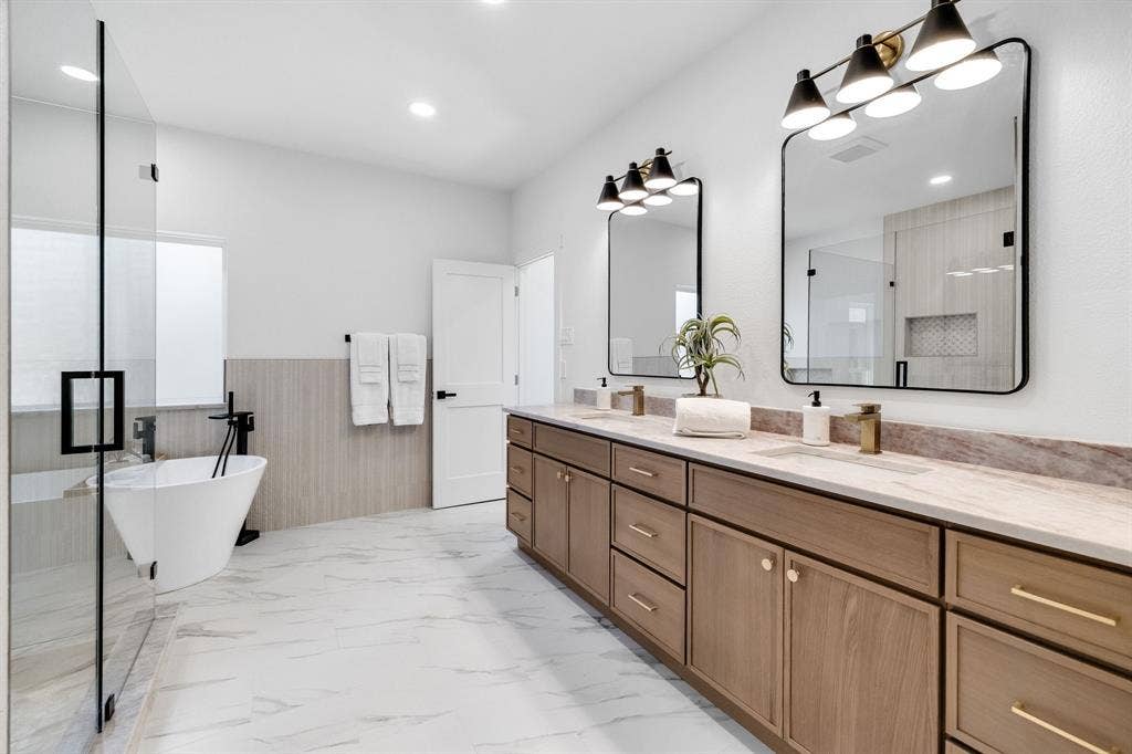 4402 Briargrove Lane, Dallas, TX 75287 4402 Briargrove-Dual vanity featuring warm wood cabinetry, rectangular sinks, and elegant gold-tone fixtures.