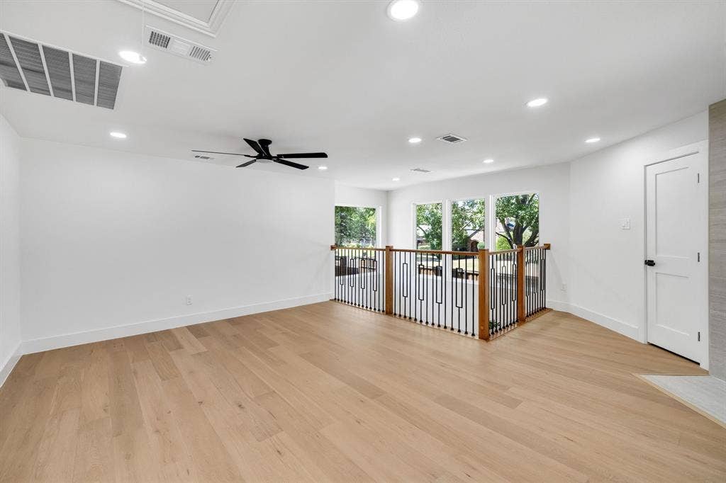4402 Briargrove Lane, Dallas, TX 75287 4402 Briargrove-Light wood-finish flooring, recessed lighting, ceiling fan, white paneled door with black hardware, and an open railing with wood and black metal balusters