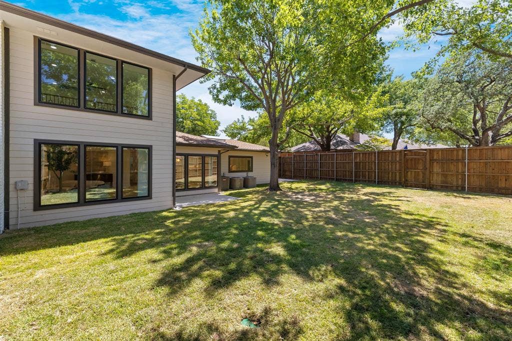 4402 Briargrove Lane, Dallas, TX 75287 4402 Briargrove-Expansive grass lawn with mature trees, a privacy fence, and a patio