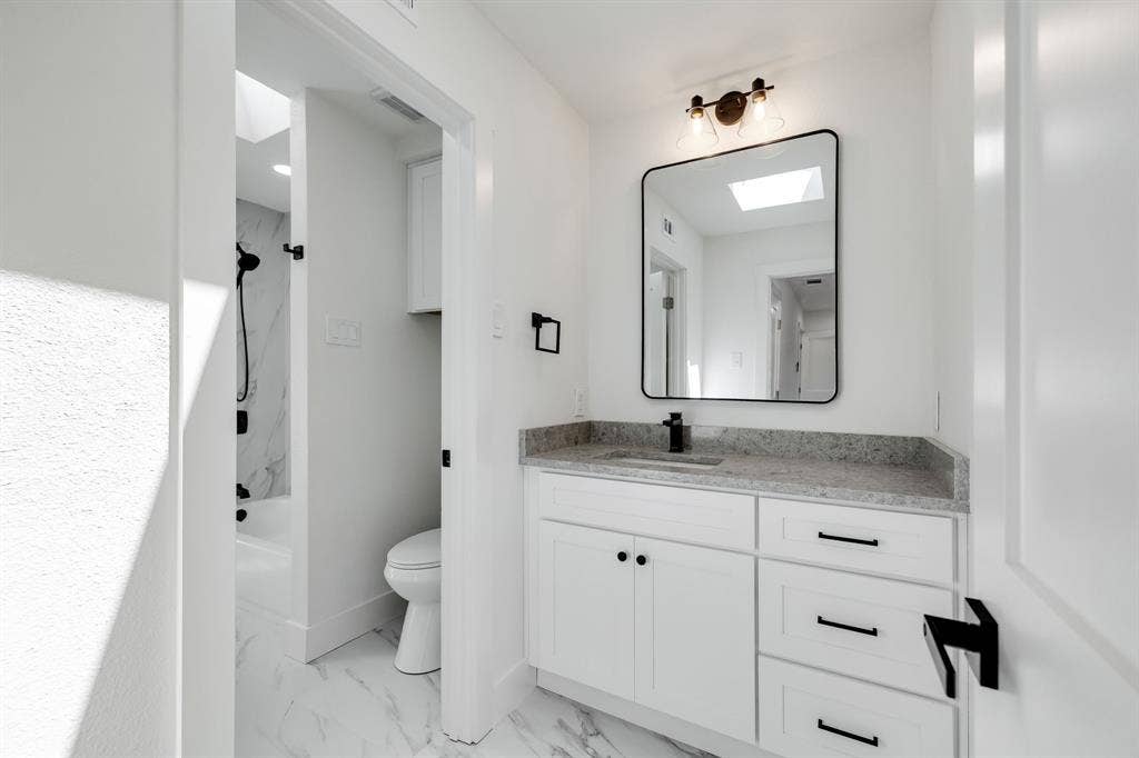 4402 Briargrove Lane, Dallas, TX 75287 4402 Briargrove-White vanity with a stone-finish countertop and undermount sink