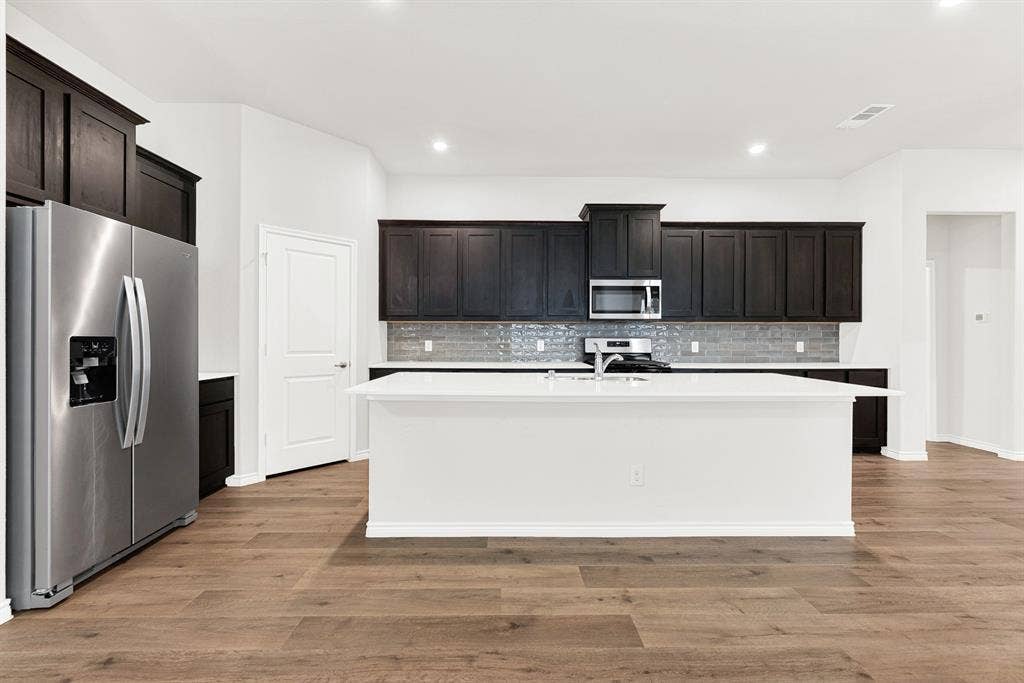 From this straight-on angle, the kitchen's wide, functional layout is clear, anchored by the oversized central island. It's the perfect central hub for casual morning breakfasts, setting out party appetizers, or just hanging out.