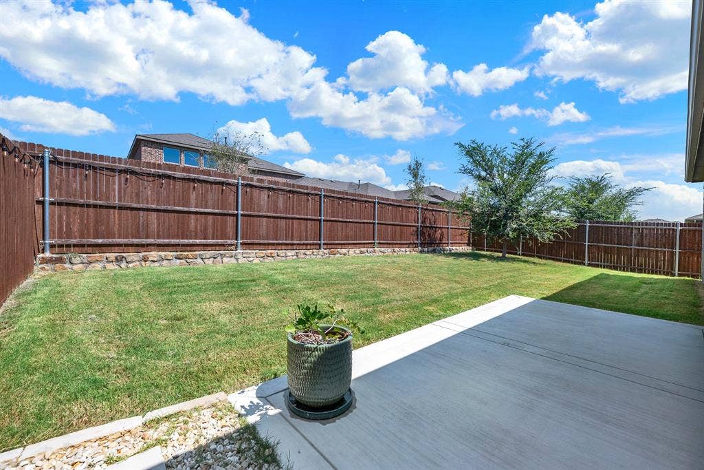 Anchored by a shady young tree, this angle showcases the deep, fully fenced backyard stretching along the retained wooden fence line. Unwind in your own peaceful sanctuary while enjoying fresh air and green surroundings right at home.