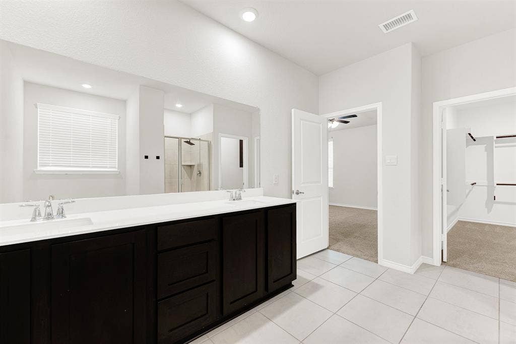 A critical viewpoint connecting all parts of the suite, this photo shows the spacious vanity, the clear flow to the main bedroom, and the entrance to the impressive walk-in closet. Effortless living defines this well-planned layout, perfectly connecting morning routines, wardrobe selection, and rest.