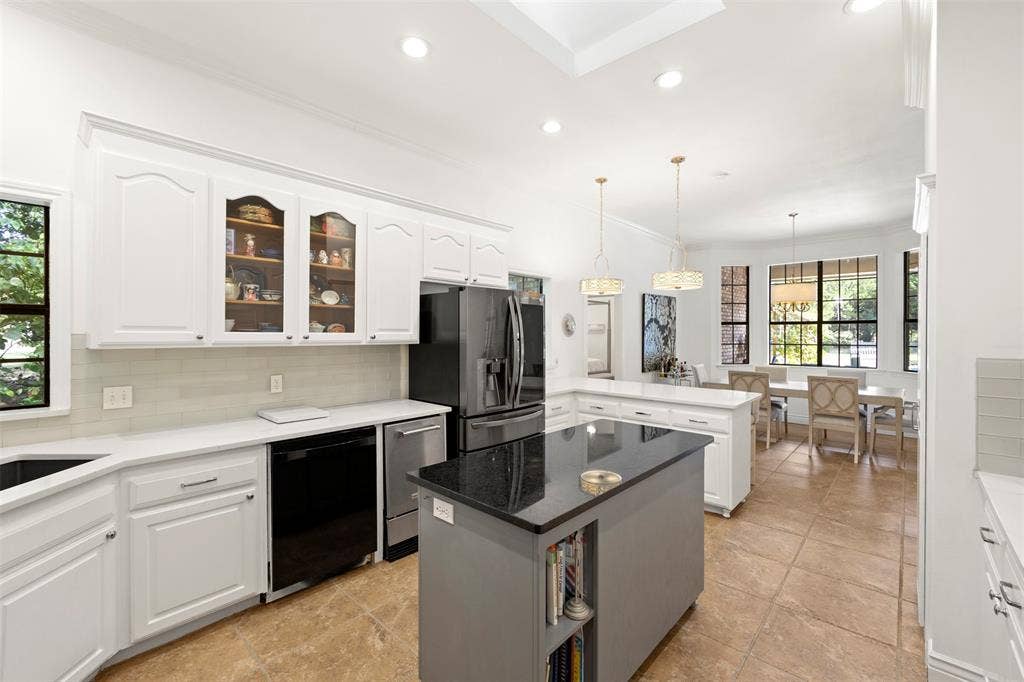 Kitchen featuring white cabinetry, a central island with a dark countertop, stainless steel appliances, and tile flooring