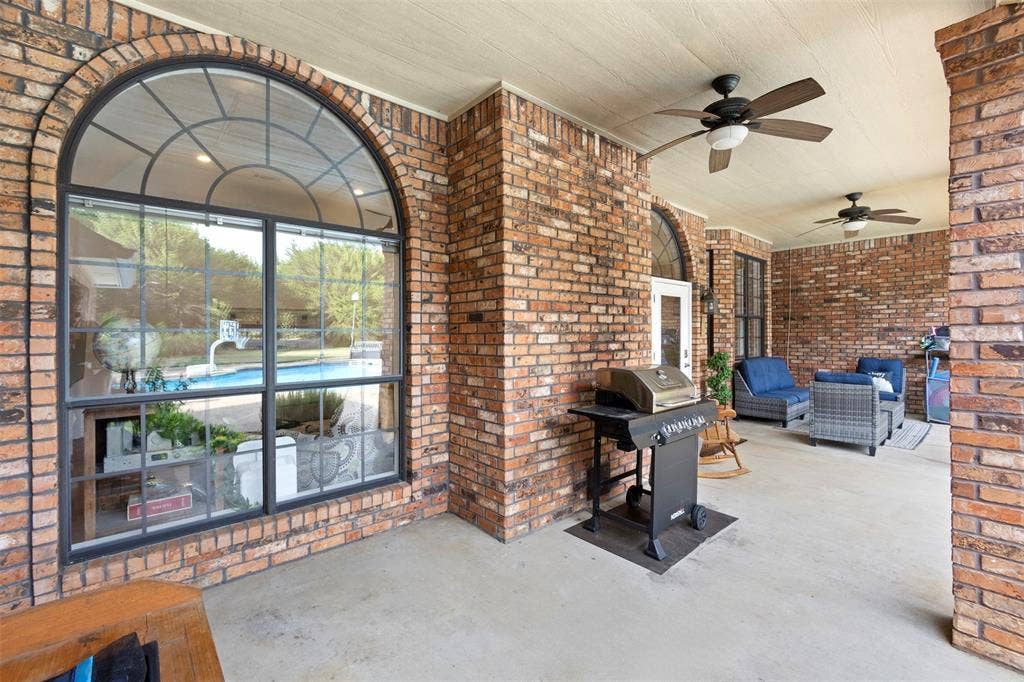 Covered outdoor patio with brick columns and walls, concrete flooring, and ceiling fans