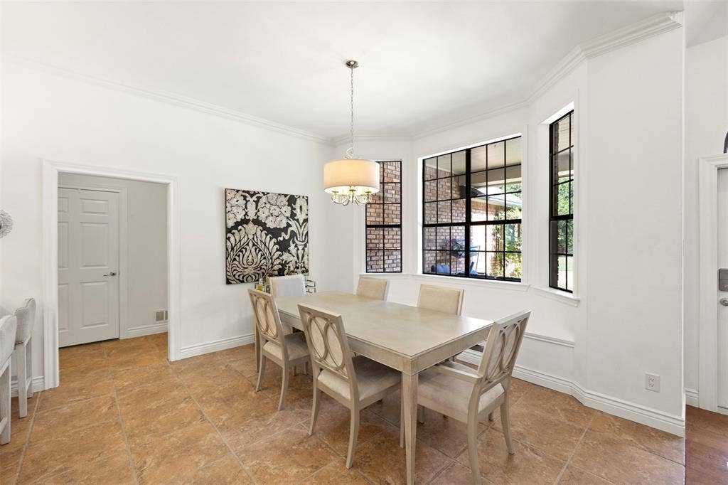 Bay window with black-framed grid panes, crown molding, drum pendant light fixture, and tile flooring