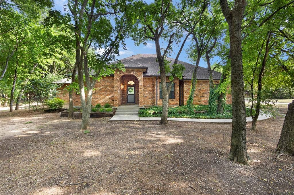 Brick exterior with arched entry, covered front porch, and established landscaping