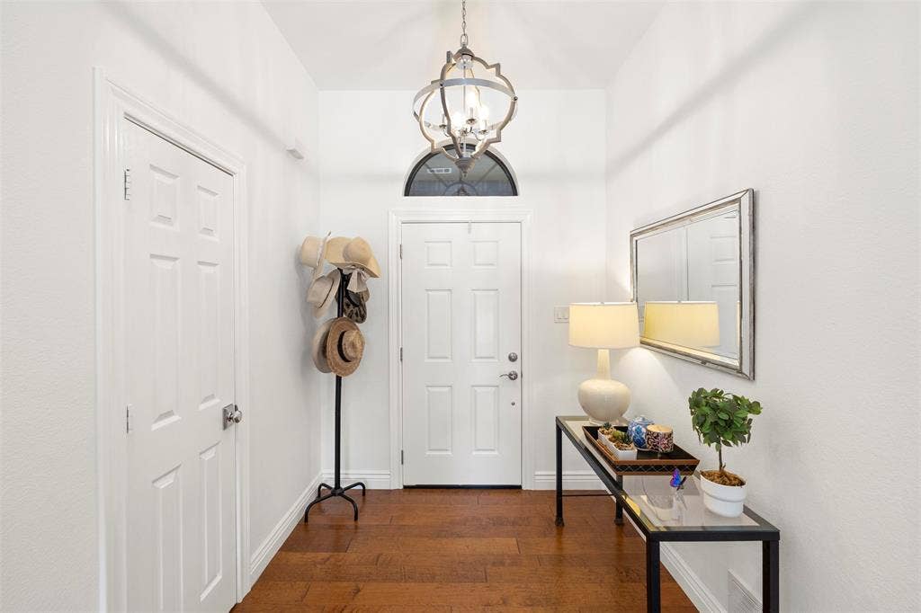 Hardwood flooring, white paneled doors, arched transom window, and a decorative pendant light fixture