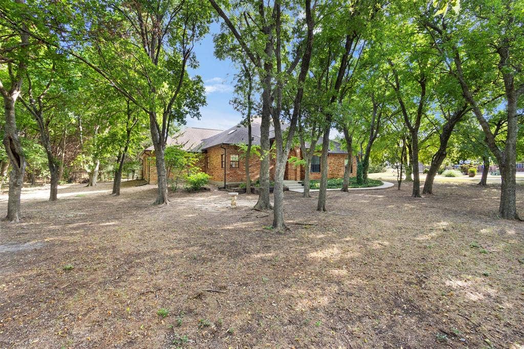 Brick exterior residence with a shingled roof, surrounded by mature trees