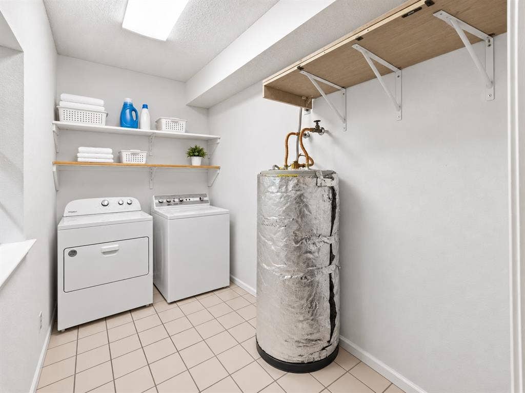 Integrated laundry area featuring tile flooring, built-in shelving, and a folding shelf