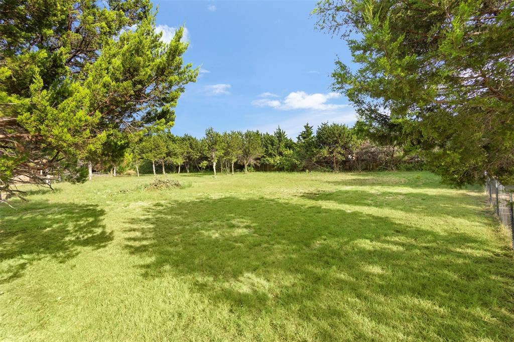 Expansive grassy area with mature trees and perimeter fencing