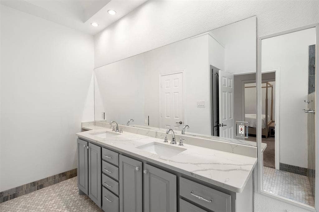 Dual vanity with integrated sinks, a continuous mirror, recessed lighting, and a hexagon tile floor