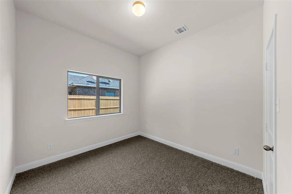 111 WATERCREST Lane, Glenn Heights, TX 75154 Neutral wall paint, textured carpet flooring, window with exterior fencing, white trim, and a ceiling-mounted light fixture