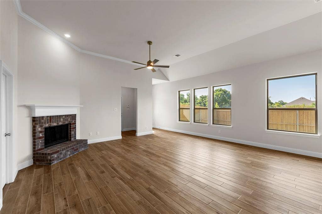 111 WATERCREST Lane, Glenn Heights, TX 75154 Vaulted ceilings with crown molding, brick fireplace with white mantel, wood-finish flooring, and multiple windows