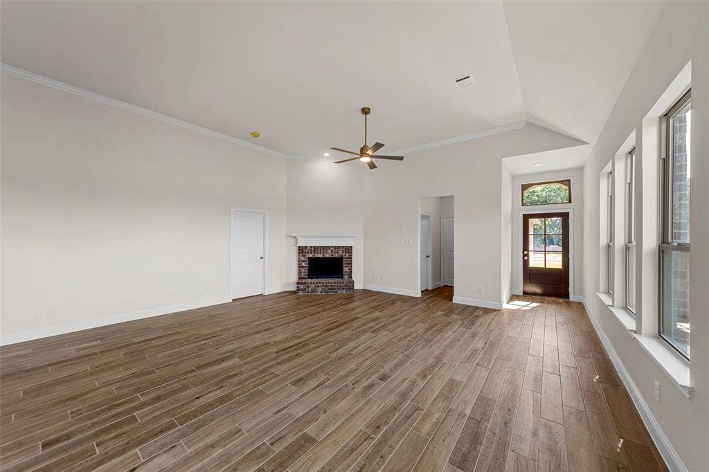 111 WATERCREST Lane, Glenn Heights, TX 75154 Spacious living area featuring wood-finish flooring, a vaulted ceiling, and a brick fireplace
