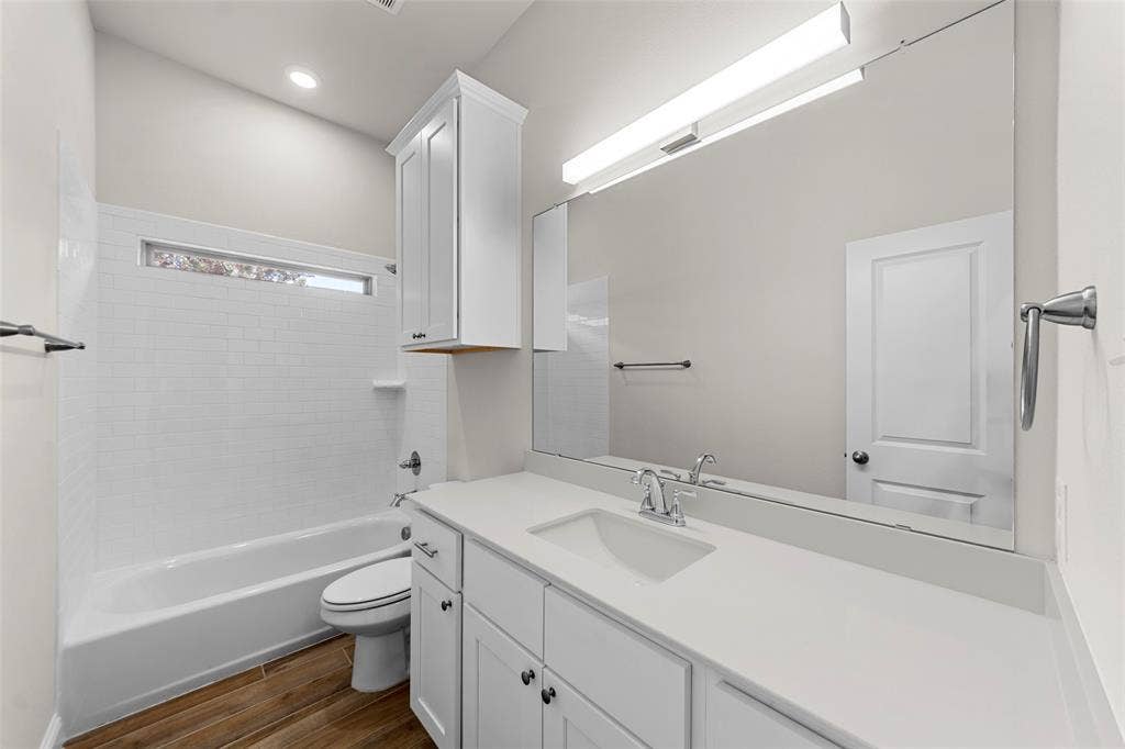 111 WATERCREST Lane, Glenn Heights, TX 75154 Bathroom featuring a white subway tile tub surround, wood-finish flooring, a single vanity with stone countertop, and recessed lighting