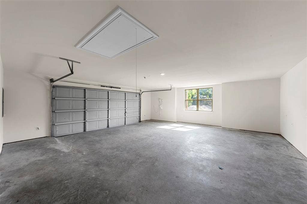 111 WATERCREST Lane, Glenn Heights, TX 75154 Spacious garage with concrete flooring, a large overhead door, an access panel, and a window