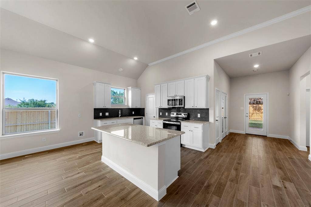 111 WATERCREST Lane, Glenn Heights, TX 75154 Vaulted ceiling, recessed lighting, wood-finish flooring, white cabinetry, and a kitchen island with a stone countertop