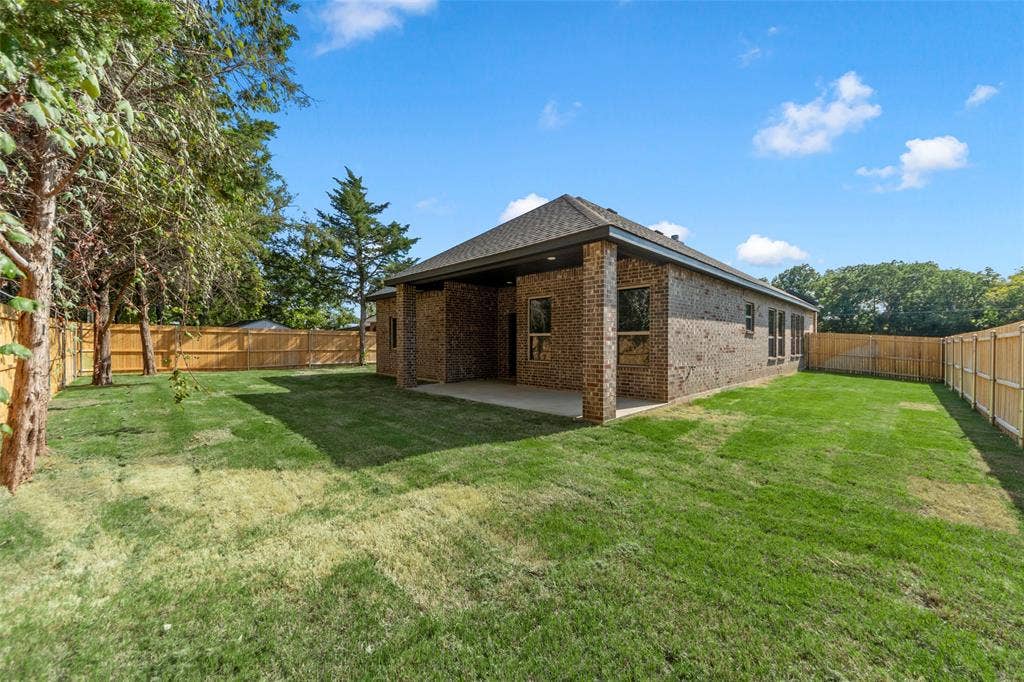 111 WATERCREST Lane, Glenn Heights, TX 75154 Brick exterior with a covered patio, expansive lawn, and wood privacy fencing