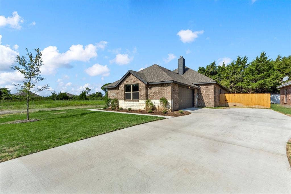 111 WATERCREST Lane, Glenn Heights, TX 75154 Brick and stone-veneer exterior with a two-car garage, concrete driveway, front lawn, and wood privacy fence