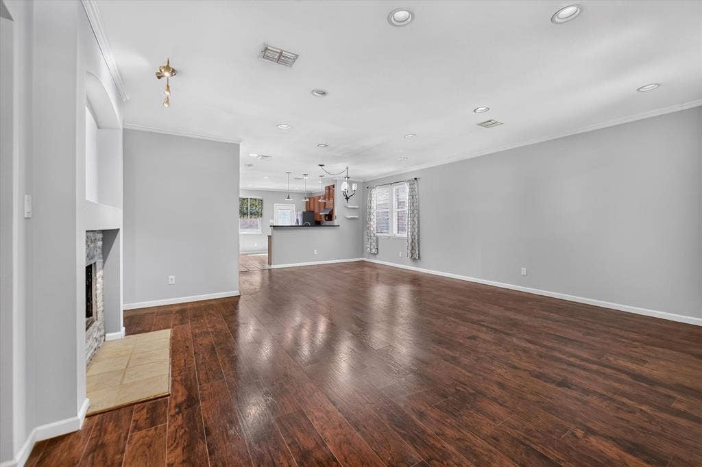 6513 Cartier Court, McKinney, TX 75072 Wood-finish flooring throughout, recessed ceiling lighting, a stone-clad fireplace with a hearth, and crown molding