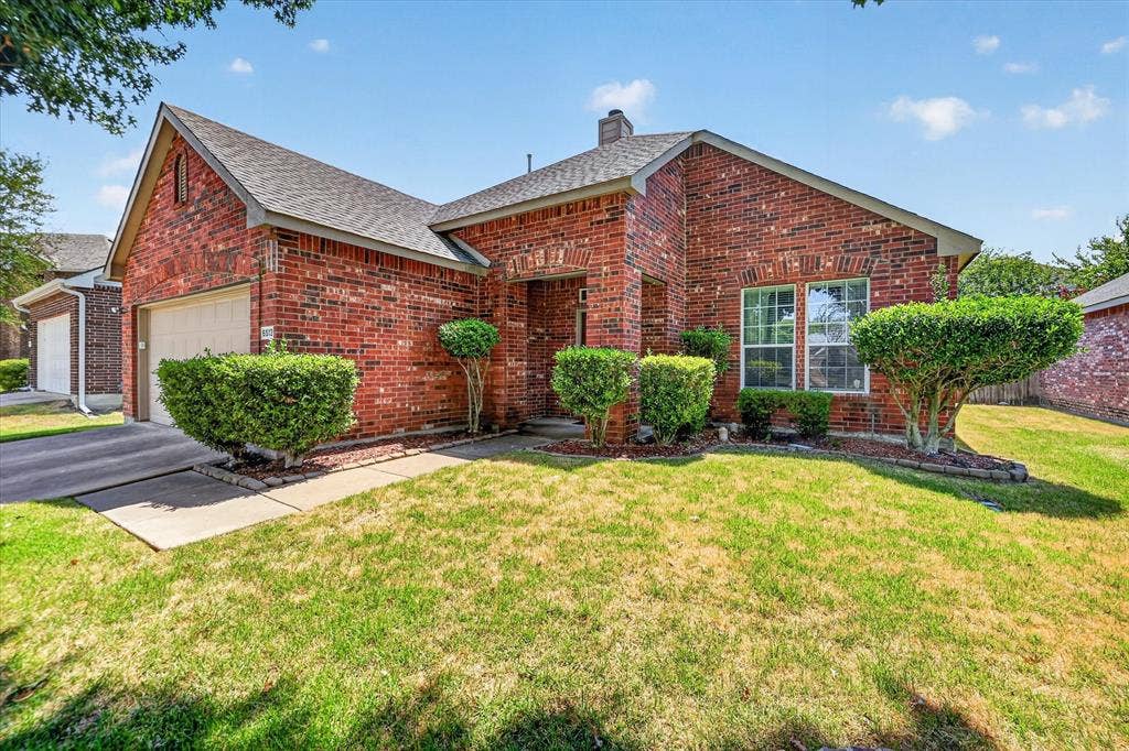 6513 Cartier Court, McKinney, TX 75072 Red brick exterior with a grey shingle roof, attached garage, and landscaping