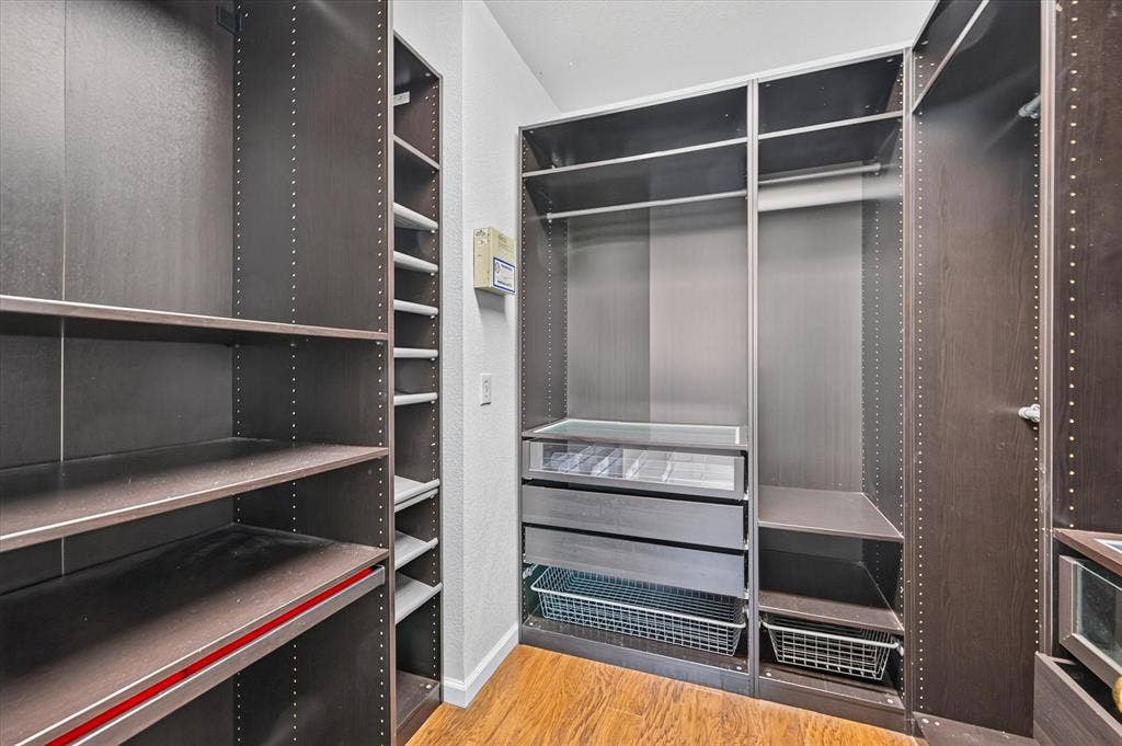 6513 Cartier Court, McKinney, TX 75072 Custom closet system featuring wood-finish flooring, multiple shelving units, integrated drawers, and wire baskets