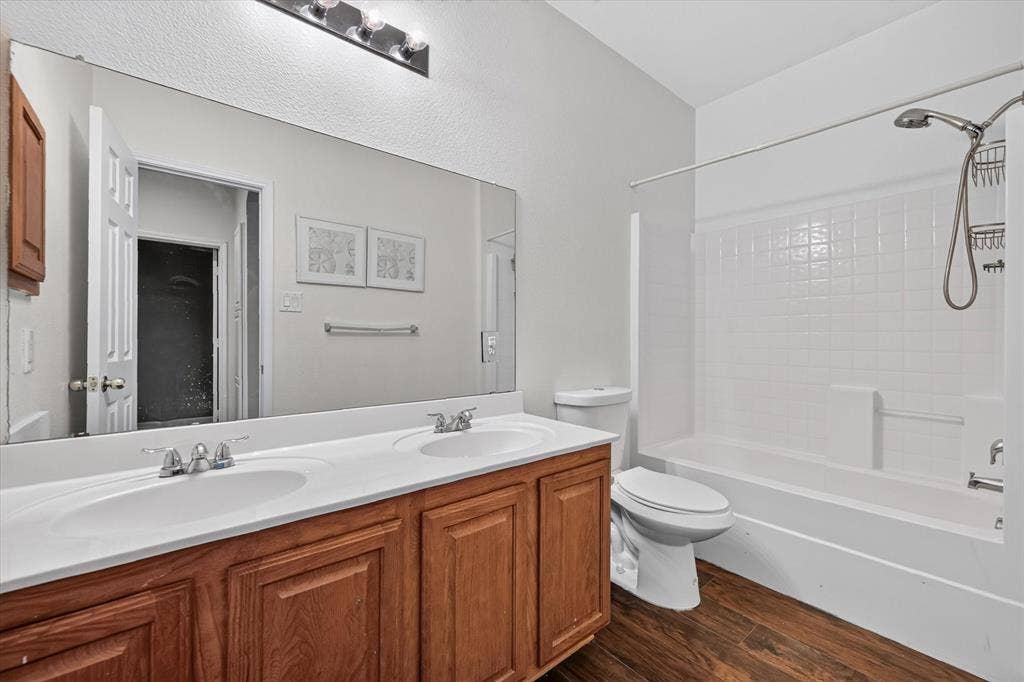 6513 Cartier Court, McKinney, TX 75072 Dual vanity with integrated sinks, wood-finish cabinetry, a full-width mirror, and overhead lighting