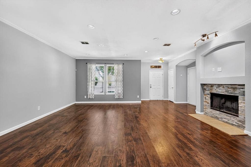 6513 Cartier Court, McKinney, TX 75072 Spacious living area featuring wood-finish flooring, recessed lighting, and a stacked stone fireplace with an arched alcove