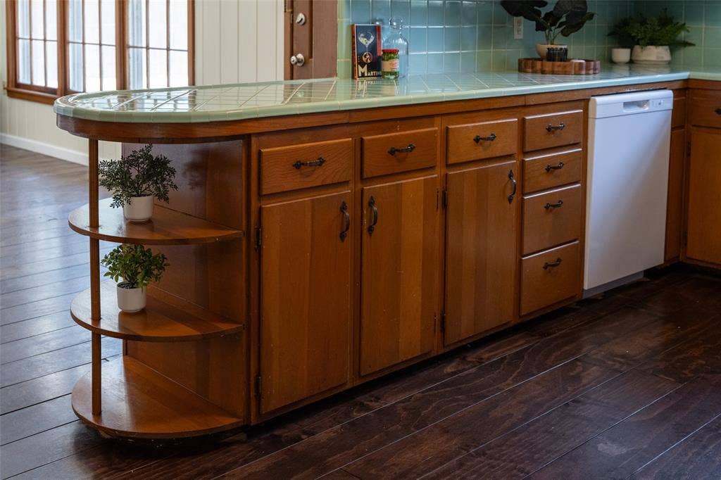 3807 Huaco Lane, Waco, TX 76710 Wood-finish flooring, custom wood cabinetry, tile countertop, tile backsplash, and a built-in dishwasher
