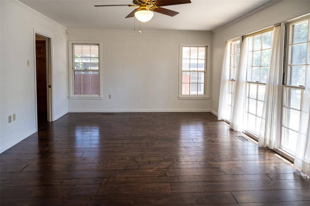 3807 Huaco Lane, Waco, TX 76710 Dark wood-finish flooring, multiple windows, ceiling fan with light fixture, and crown molding