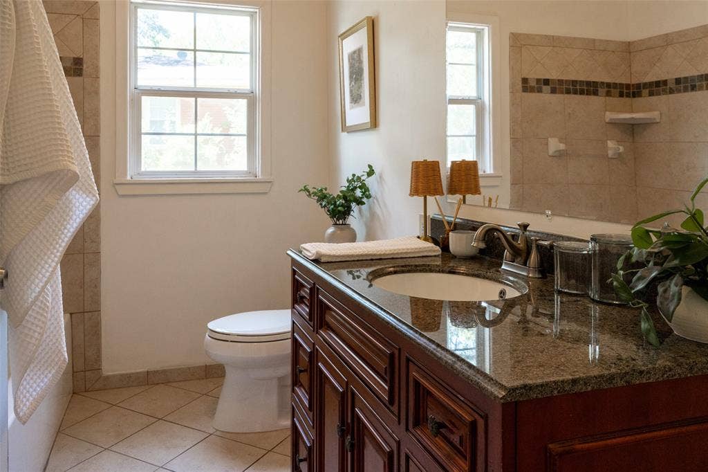 3807 Huaco Lane, Waco, TX 76710 Wood-finish vanity with an undermount sink, stone countertop, and brass-finish faucet