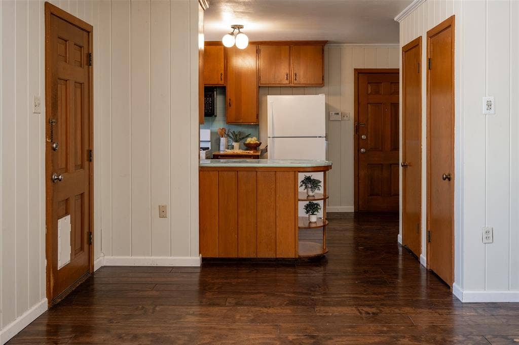 3807 Huaco Lane, Waco, TX 76710 Wood-finish flooring, vertical paneling, wood cabinetry, and a built-in refrigerator