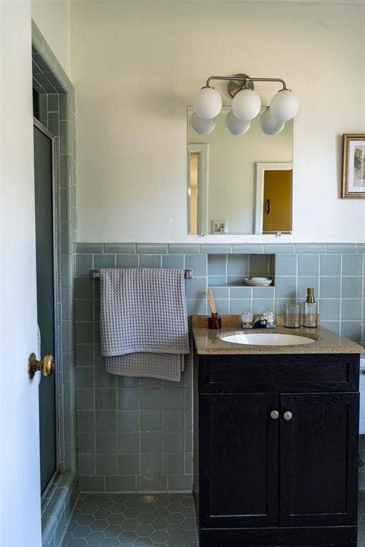 3807 Huaco Lane, Waco, TX 76710 Bathroom featuring a dark wood vanity with a light-toned countertop, an undermount sink, and a mirrored wall cabinet