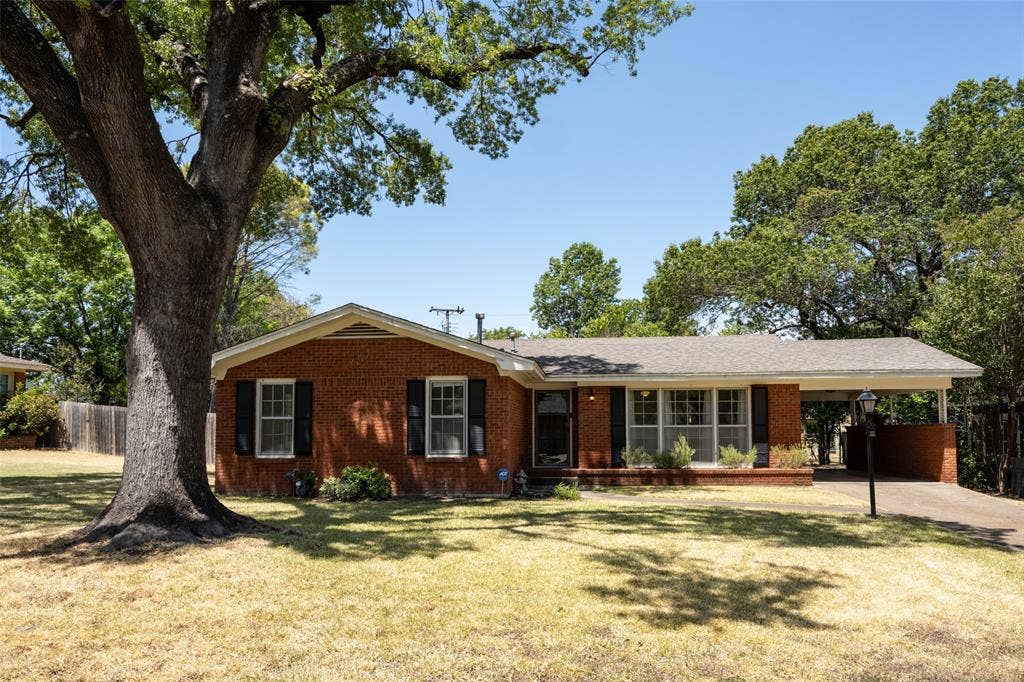3807 Huaco Lane, Waco, TX 76710 Brick exterior with a gabled roof, covered carport, and mature front yard tree