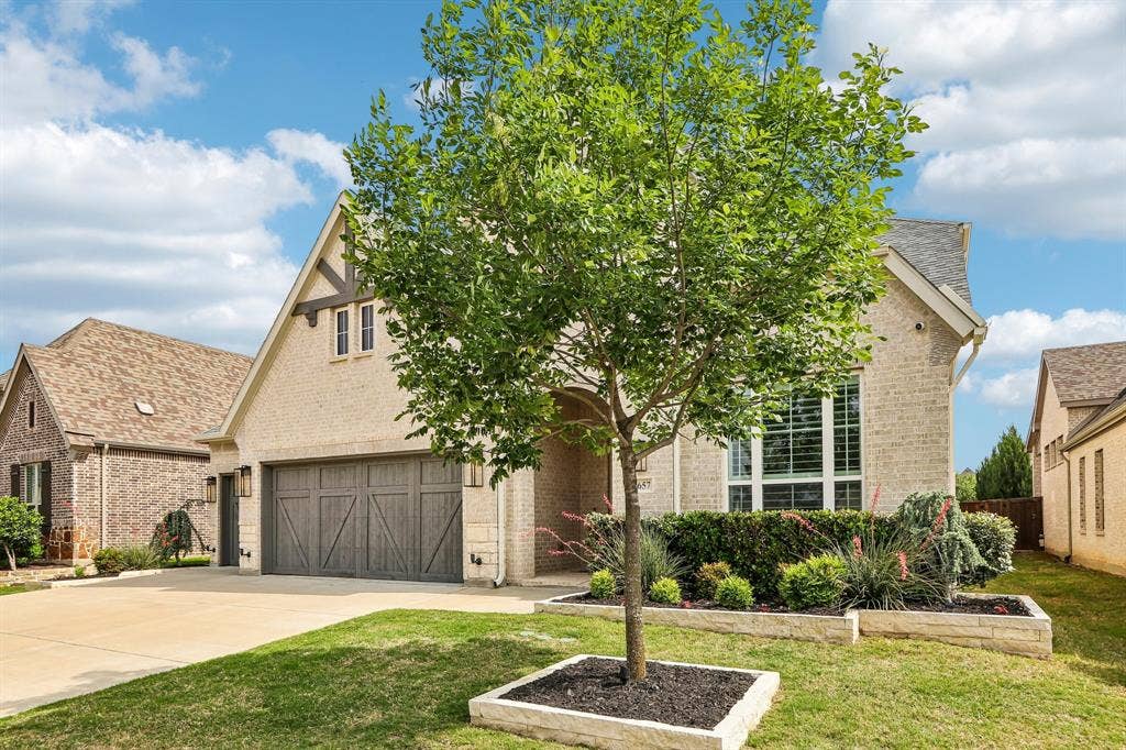 1657 Lilac Lane, Celina, TX 75009 Brick exterior with stone accents, gable roofline, decorative garage door, and established landscaping