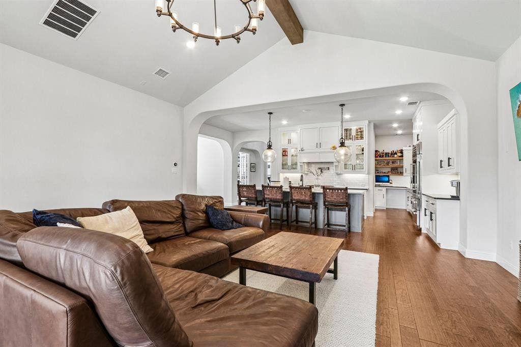 1657 Lilac Lane, Celina, TX 75009 Vaulted ceiling with an exposed beam, hardwood flooring, recessed lighting, arched doorways, and a kitchen featuring white cabinetry