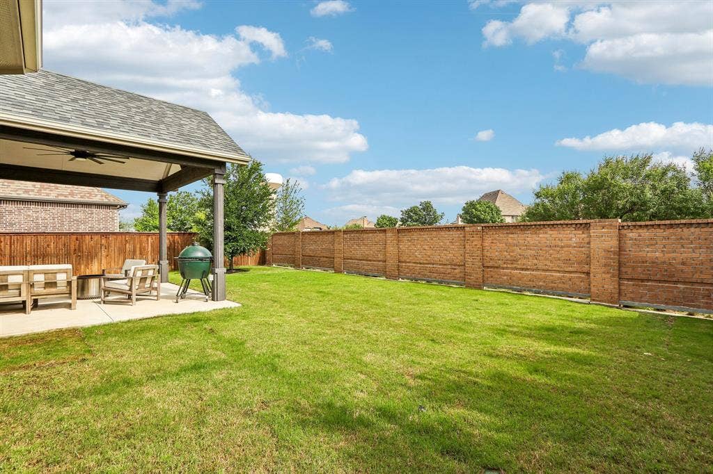 1657 Lilac Lane, Celina, TX 75009 Expansive lawn with a covered patio, featuring an outdoor ceiling fan, and a wood privacy fence