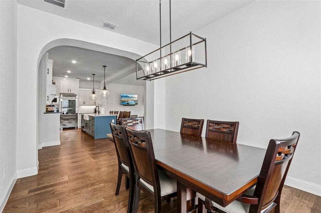 1657 Lilac Lane, Celina, TX 75009 Arched entryway leading to a kitchen with stainless steel appliances, a center island with a built-in sink, and pendant lighting